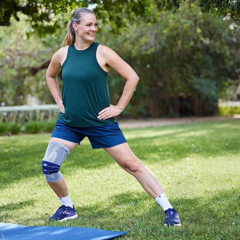 Image of a woman wearing Bauerfeind's GenuTrain knee brace while hiking up a rocky mountain trail.