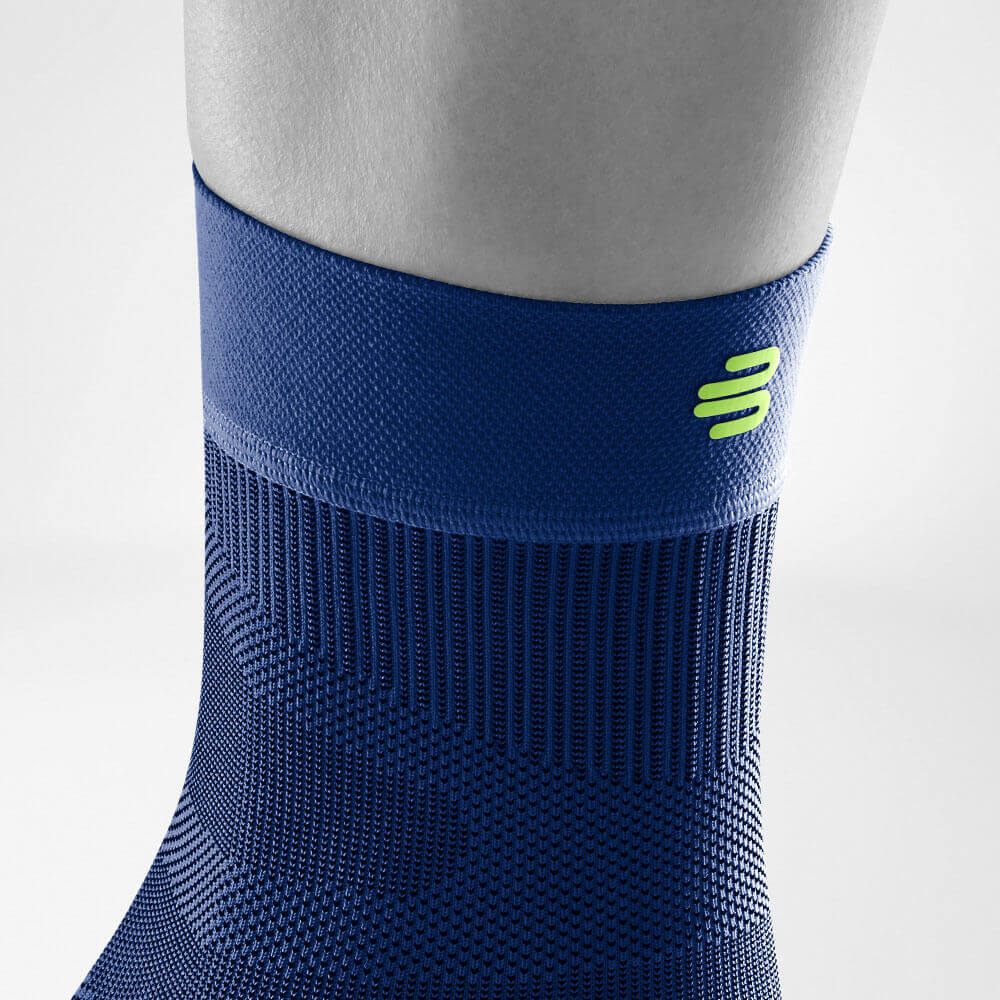 Close-up of a person's ankle wearing a blue compression sock with a green logo