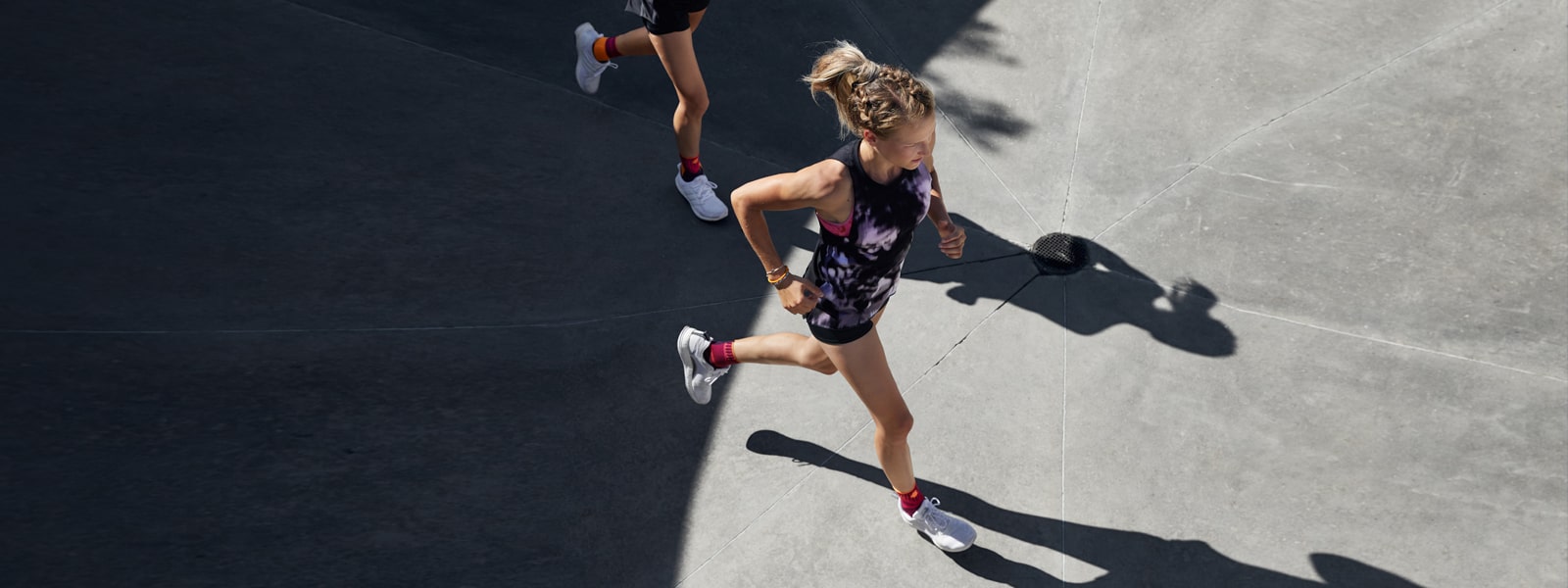 Two women running outside while wearing Bauerfeind's Sports Ankle Support.