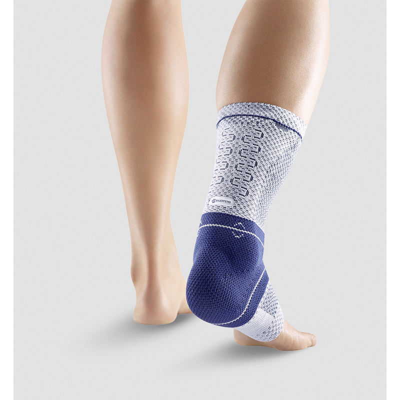 Close-up view of a person wearing a blue and white ankle support brace demonstrating its fit and design on a neutral background