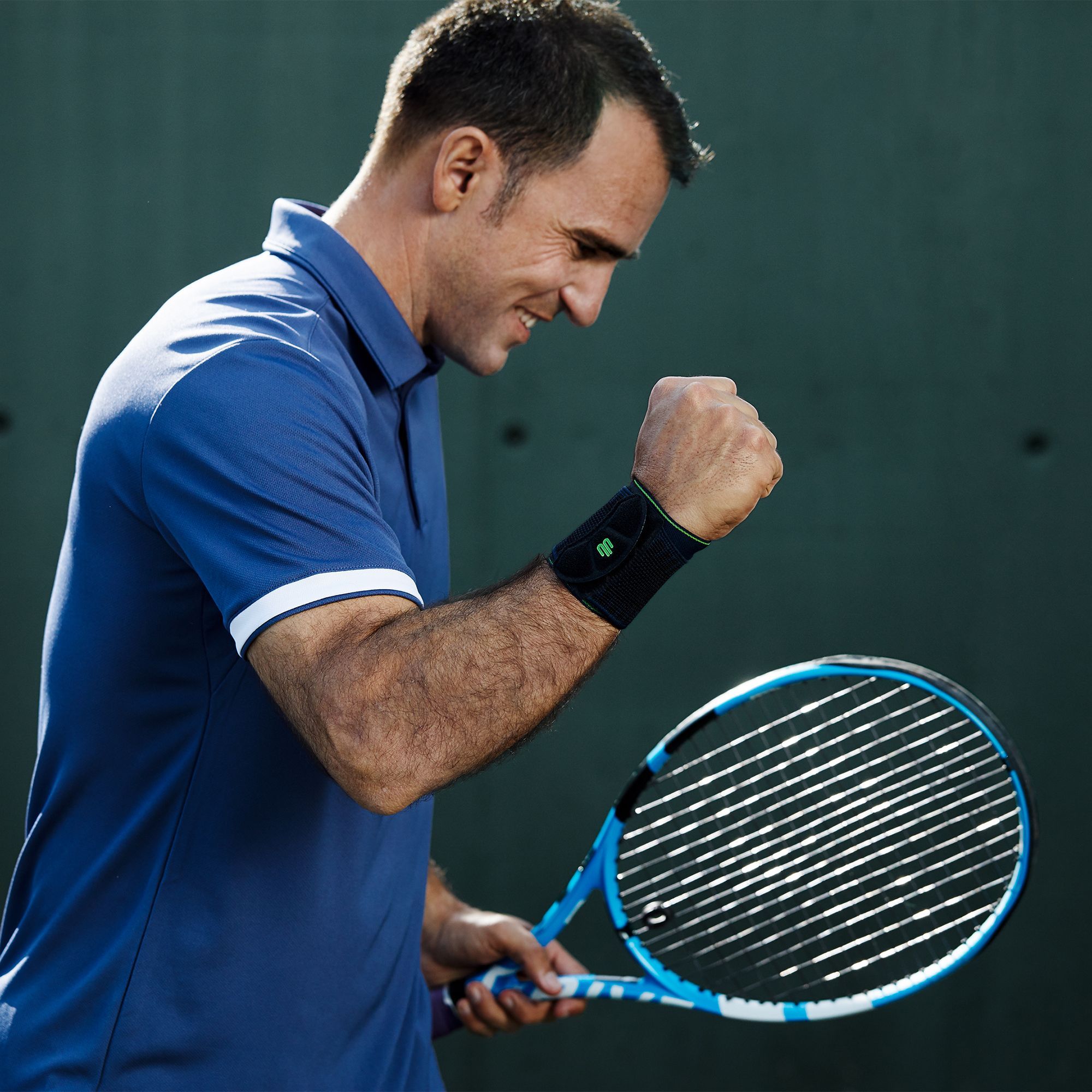 Image of a tennis player celebrating during a match while wearing Bauerfeind's Sports Wrist Strap.