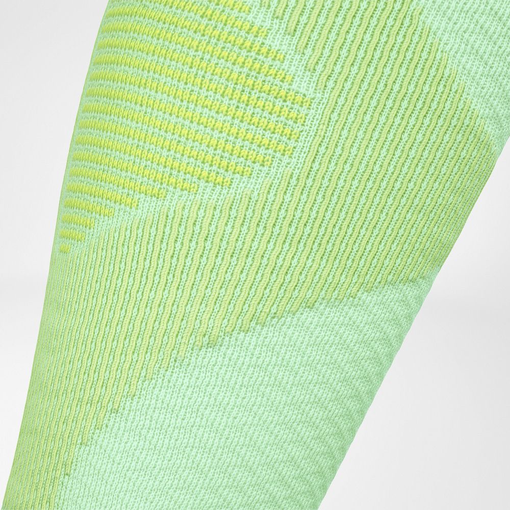 Close-up of light green sports fabric with moisture-wicking technology and subtle yellow stripe design