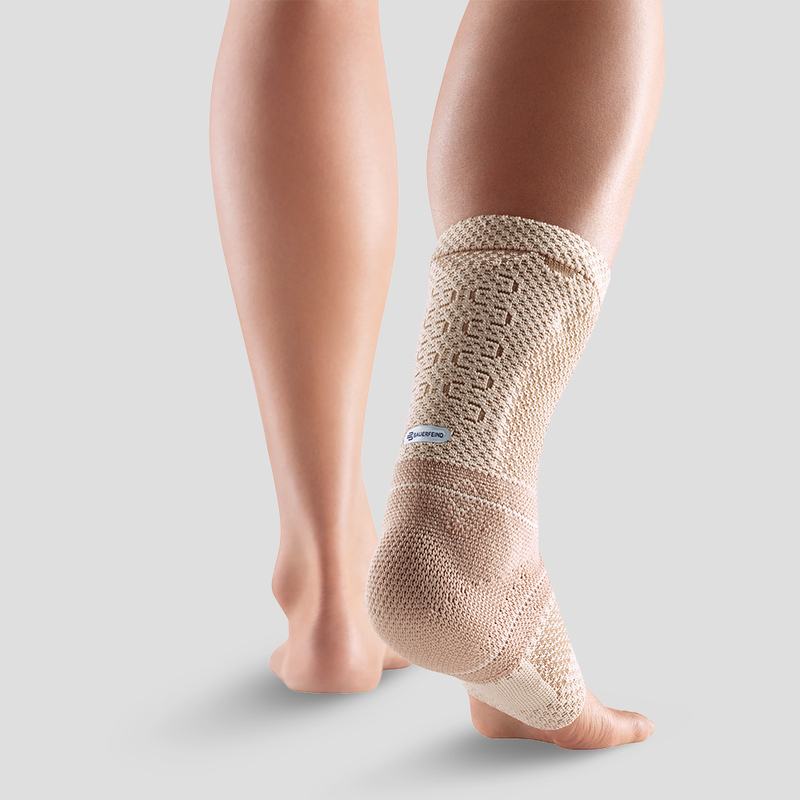 Close-up view of a person wearing a blue and white ankle support brace demonstrating its fit and design on a neutral background