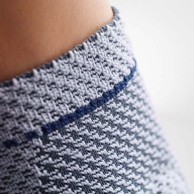 Close-up view of a knitted sweater with detailed texture and a ribbed collar featuring a blue stripe