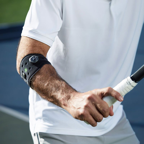 Man wearing Bauerfeind's Sports Elbow Strap while playing tennis.