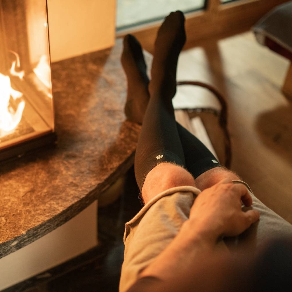 Person relaxing by a cozy fireplace with feet up, wearing black socks.