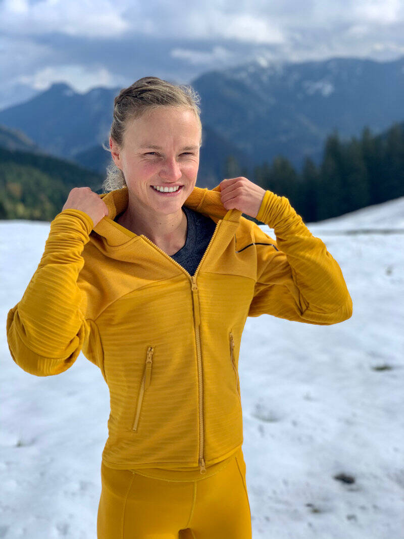 Woman adjusting the hood of her jacket before running in snowy weather. 