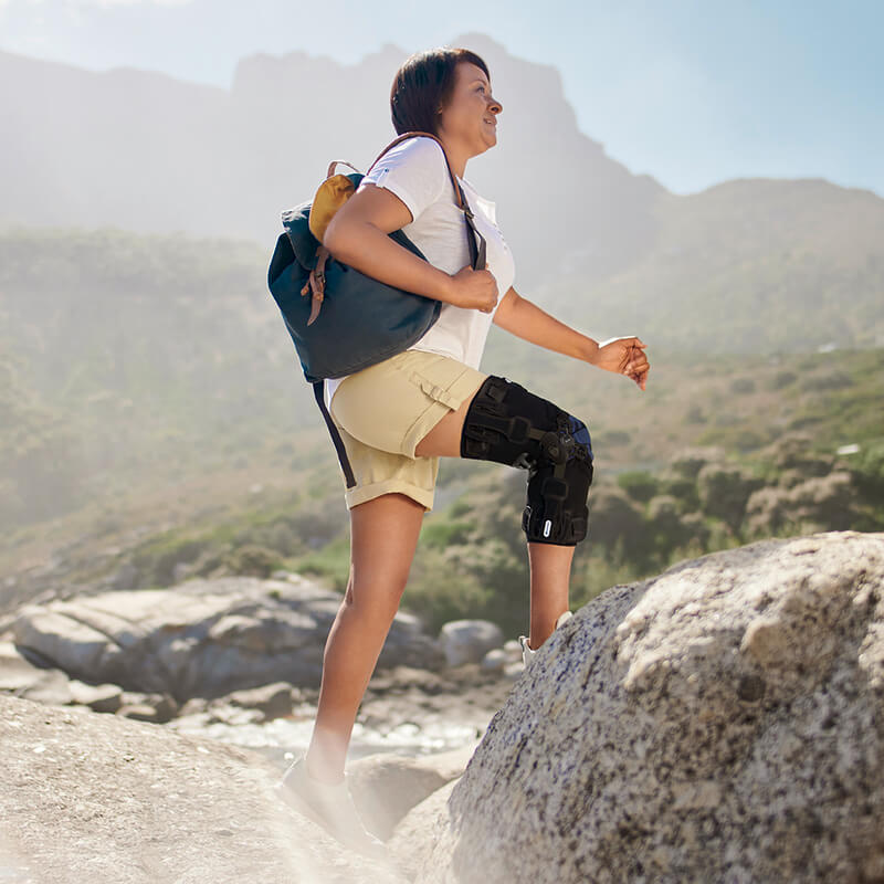 Woman with a prosthetic leg wearing a backpack hikes on a rocky mountain trail with scenic views