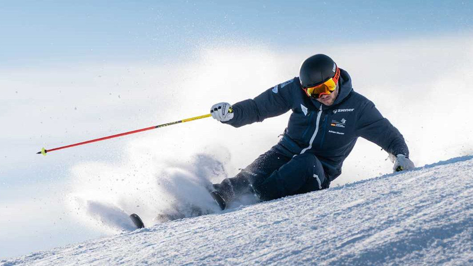 Close-up of a skier's hands holding ski poles, featuring Bauerfeind's RhizoLoc thumb spica splint, winter sportswear and gloves on a snowy background.