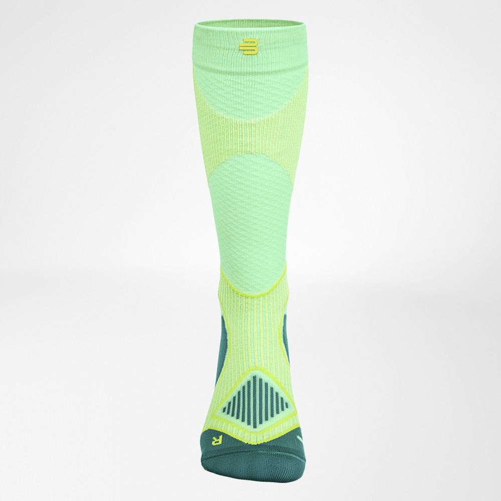 High-performance green and yellow compression sock designed for athletic use, featuring strategic padding and breathable fabric details.