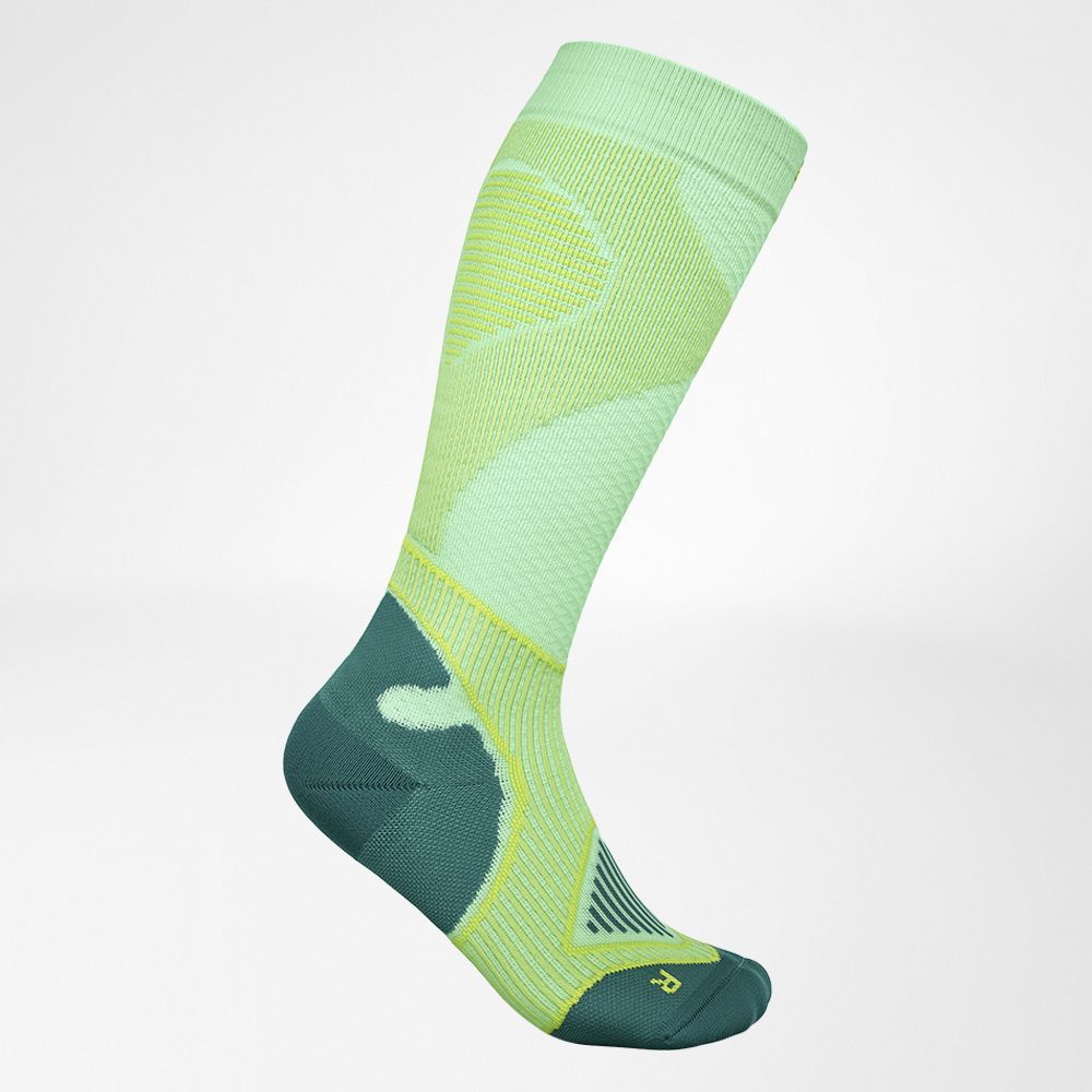 High-performance green and yellow compression sock displayed on a plain background, designed with moisture-wicking fabric and arch support for athletic use.