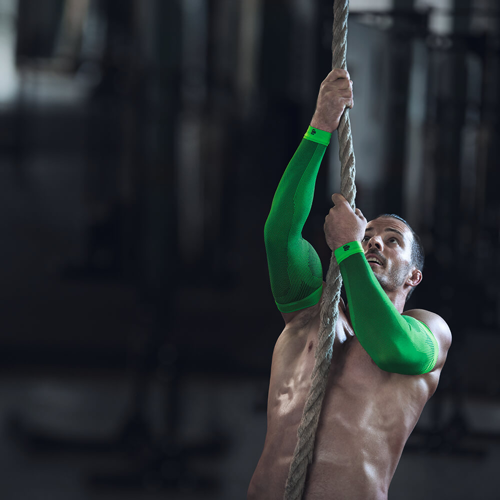 Image of athletic man climbing rope in gym wearing Sports Compression Sleeves Arm