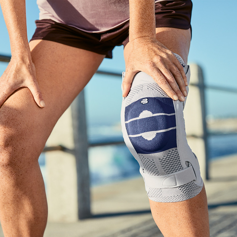 Close-up image of a woman wearing Bauerfeind's GenuTrain S hinged knee brace while resting from her run.