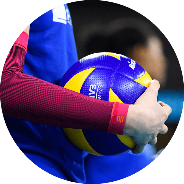 Athlete holding a volleyball while wearing Bauerfeind's Sports Compression Arm Sleeves before a match.