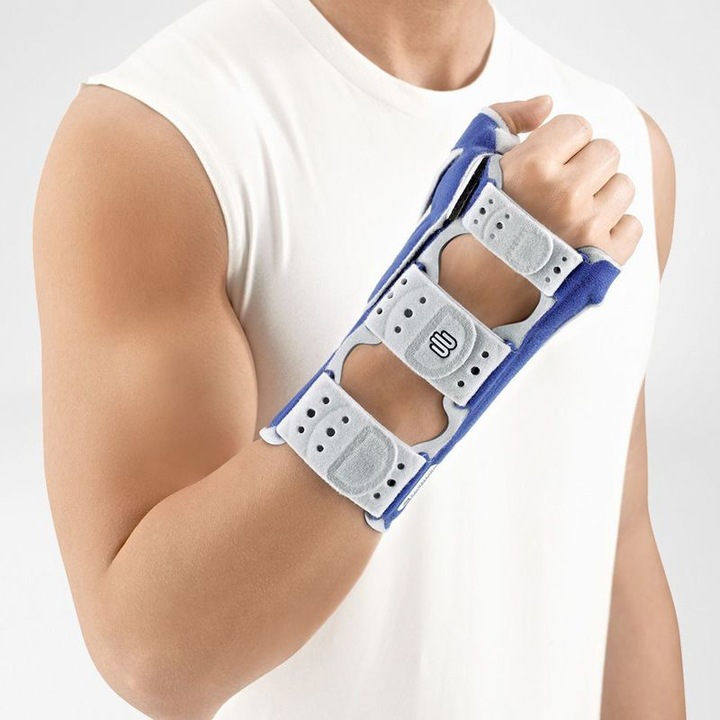 Athletic man wearing a white sleeveless shirt demonstrating a modern blue and gray wrist brace on his forearm, highlighting its adjustable features and comfortable design.