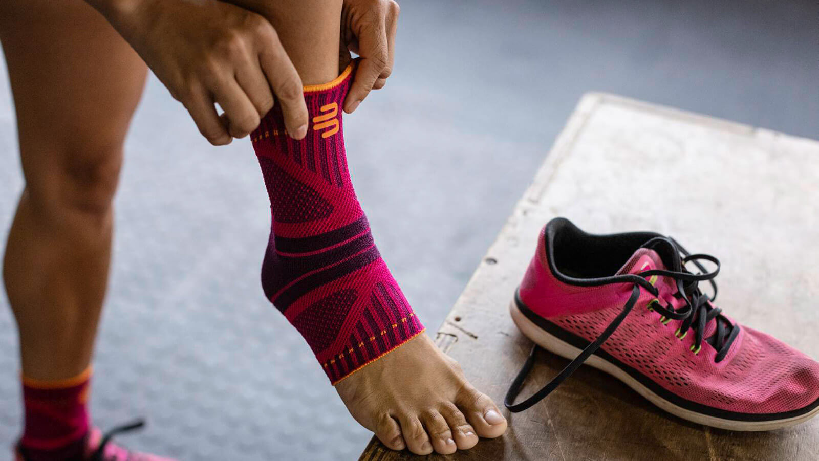 Woman donning Bauerfeind's Sports Ankle Support Dynamic before working out in a fitness center.