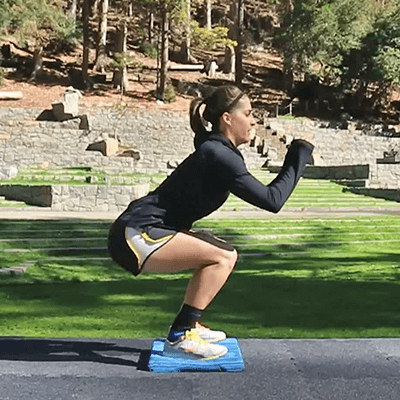 Woman performing the unstable squats exercise while in her back yard and wearing Bauerfeind's AchilloTrain Achilles tendonitis ankle brace.