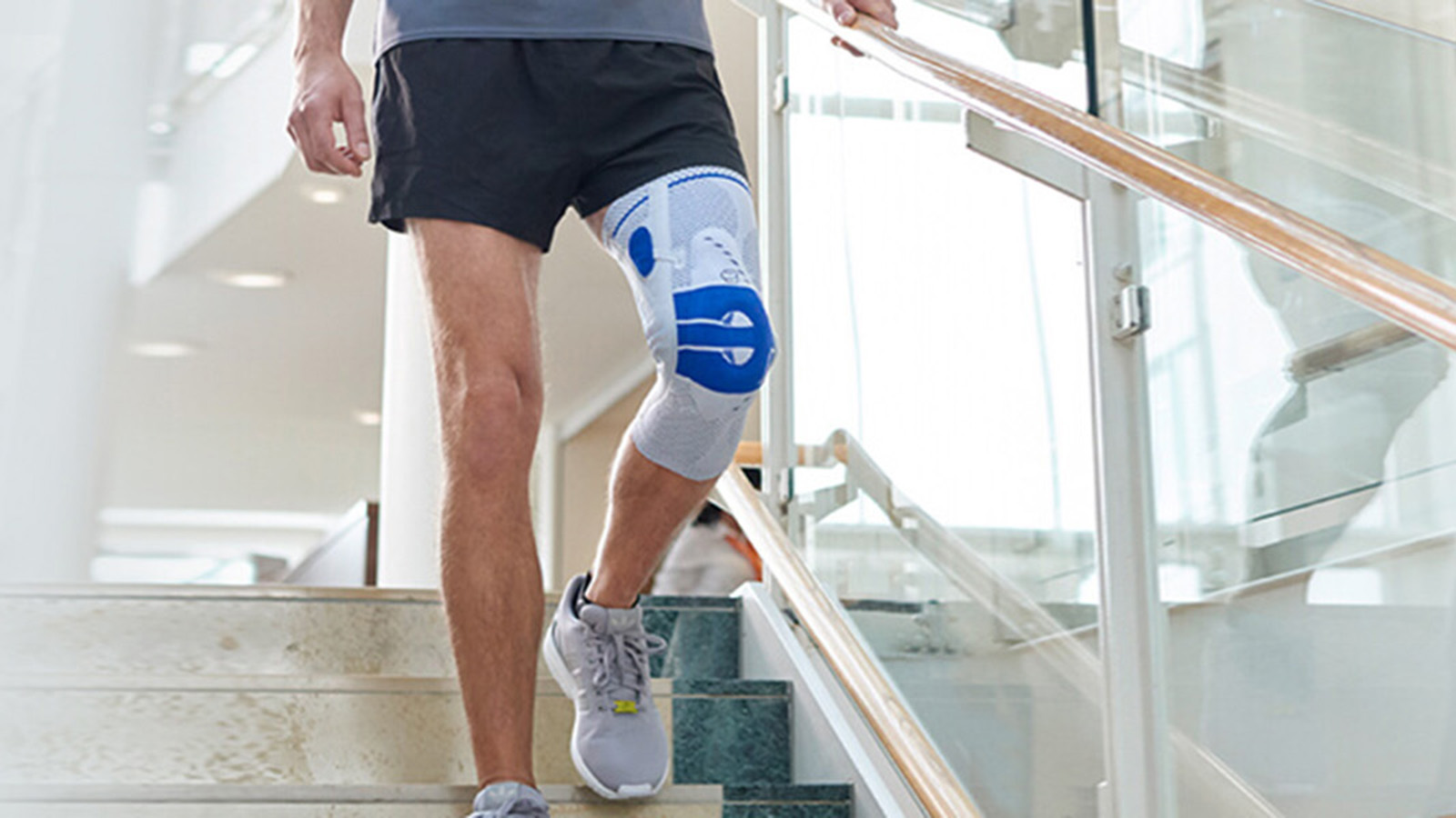 Woman practicing yoga in a fitness center while wearing Bauerfeind's GenuTrain P3 patella knee brace.