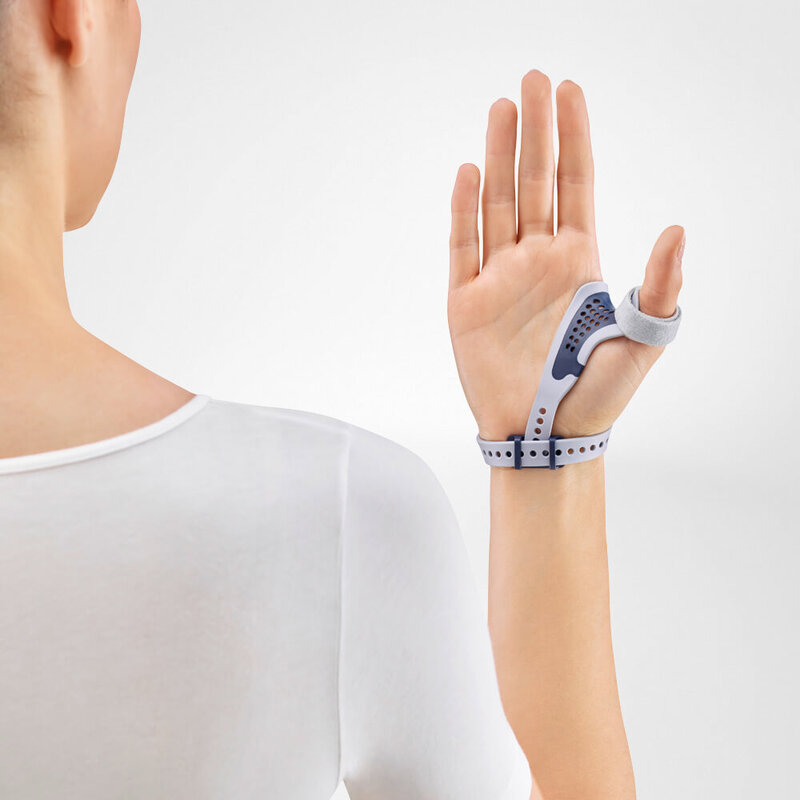 Image of a woman showing the palm side of Bauerfeind's RhizoLoc OA arthritis thumb brace in front of a gray background.