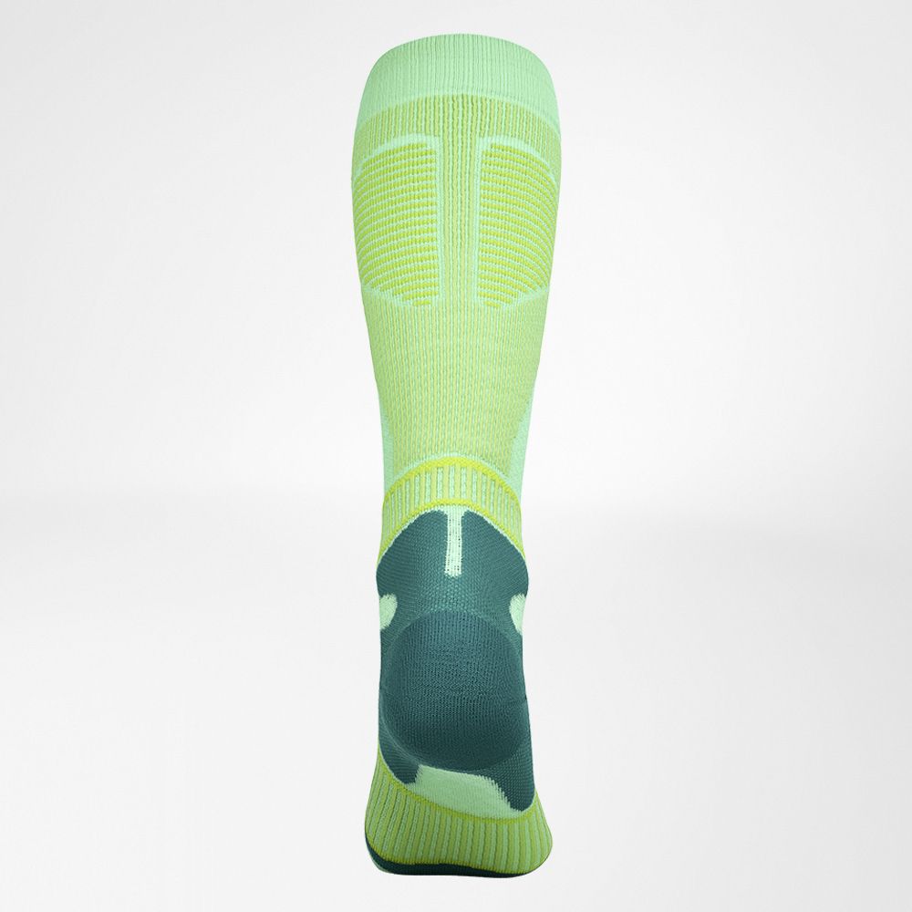 High-performance green and yellow compression soccer sock displayed on a neutral background, showing foot and ankle support zones.