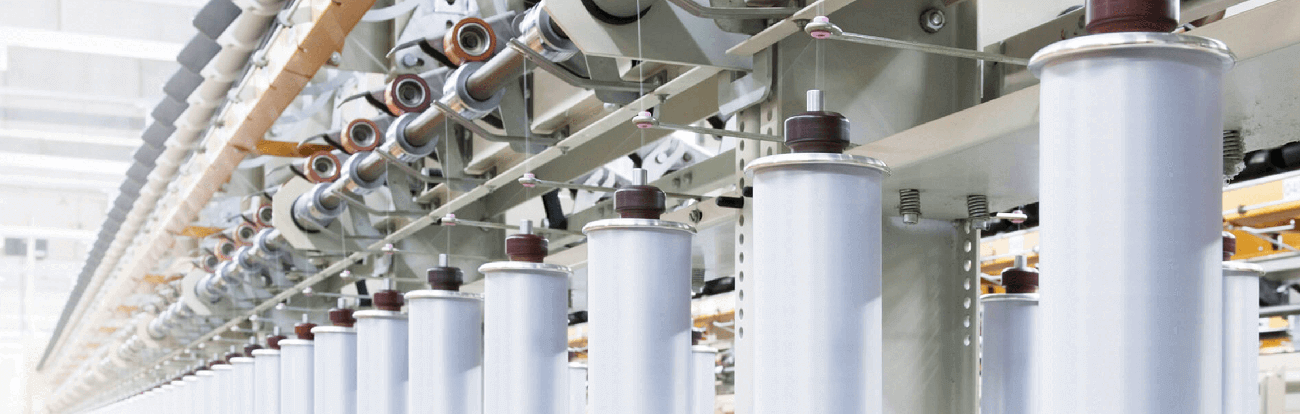 Row of textile yarn spools on industrial spinning machine in a manufacturing plant