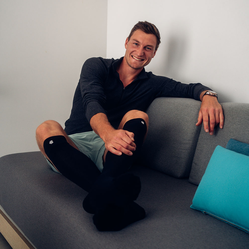 Image of man sitting on a sofa wearing Recovery Socks