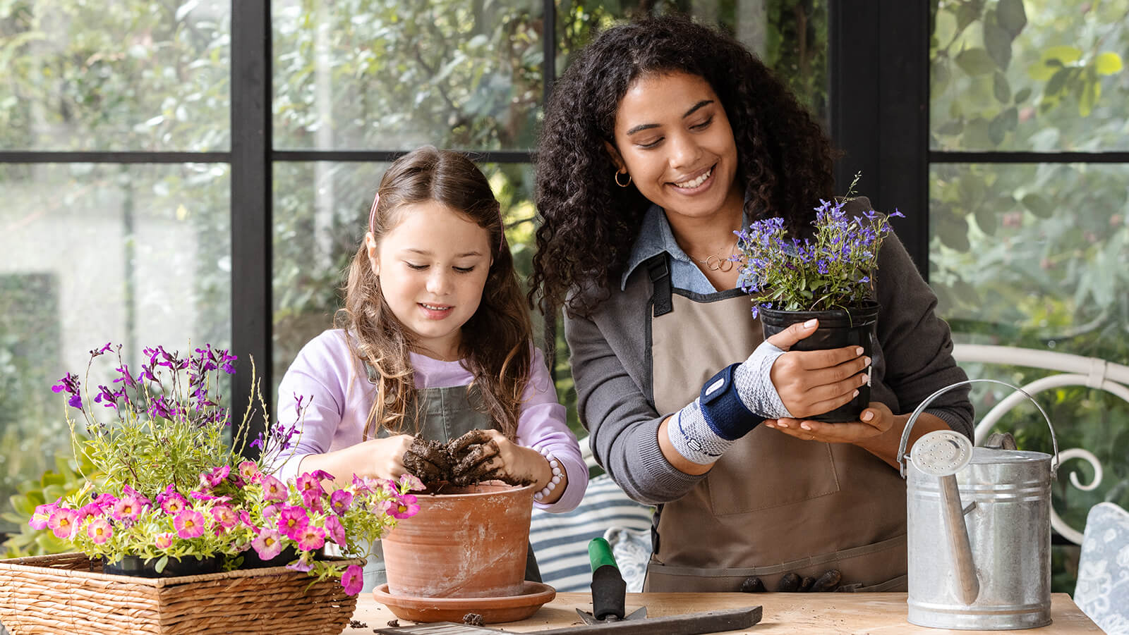 Woman planting flowers with a child while wearing Bauerfeind's ManuTrain wrist brace.