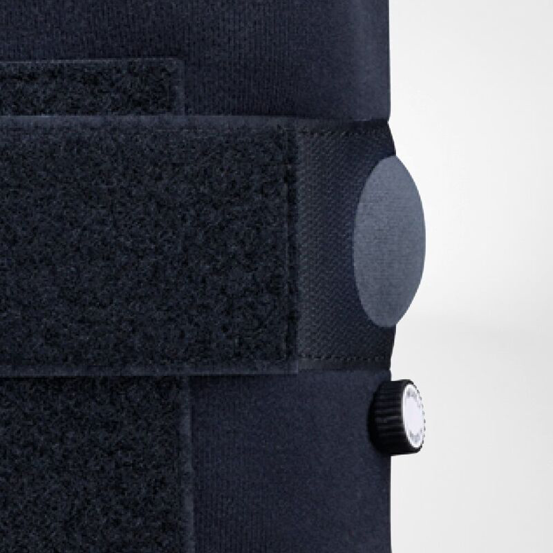 Close-up of a black adjustable knee brace with velcro fasteners and stabilizing dial