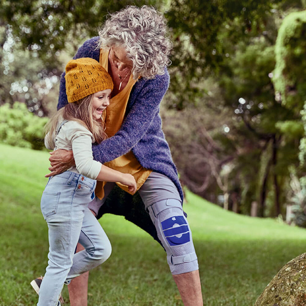 Grandmother playing outside with her granddaughter while wearing Bauerfeind's GenuTrain S knee brace.