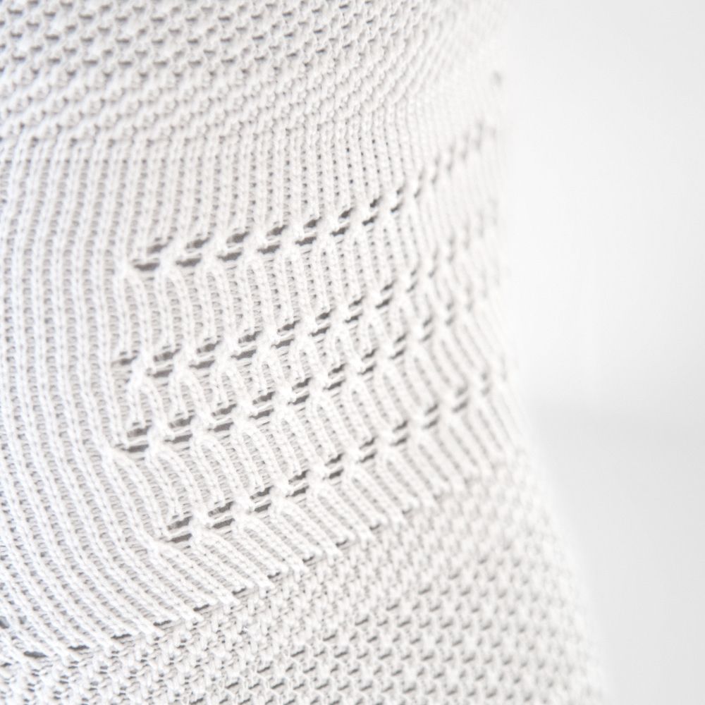 Close-up of white knitted fabric with intricate patterns and texture.