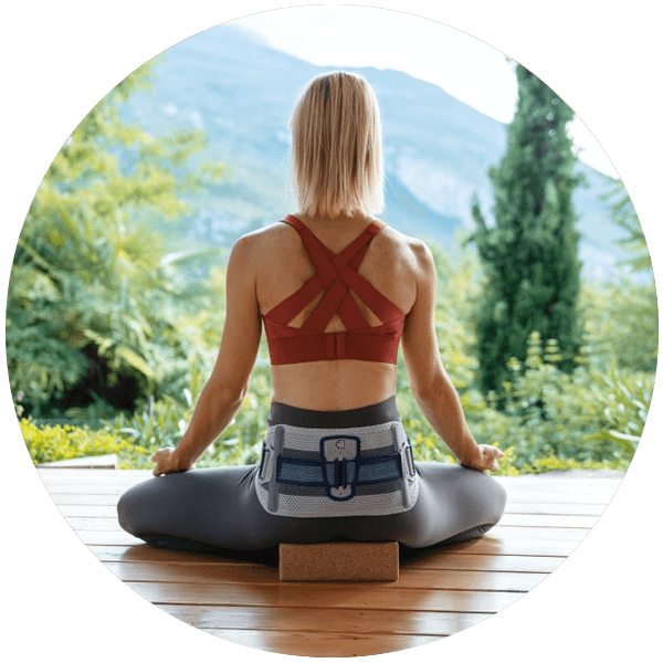 Person wearing Bauerfeind's SacroLoc SI joint belt while sitting outdoors to practice yoga.