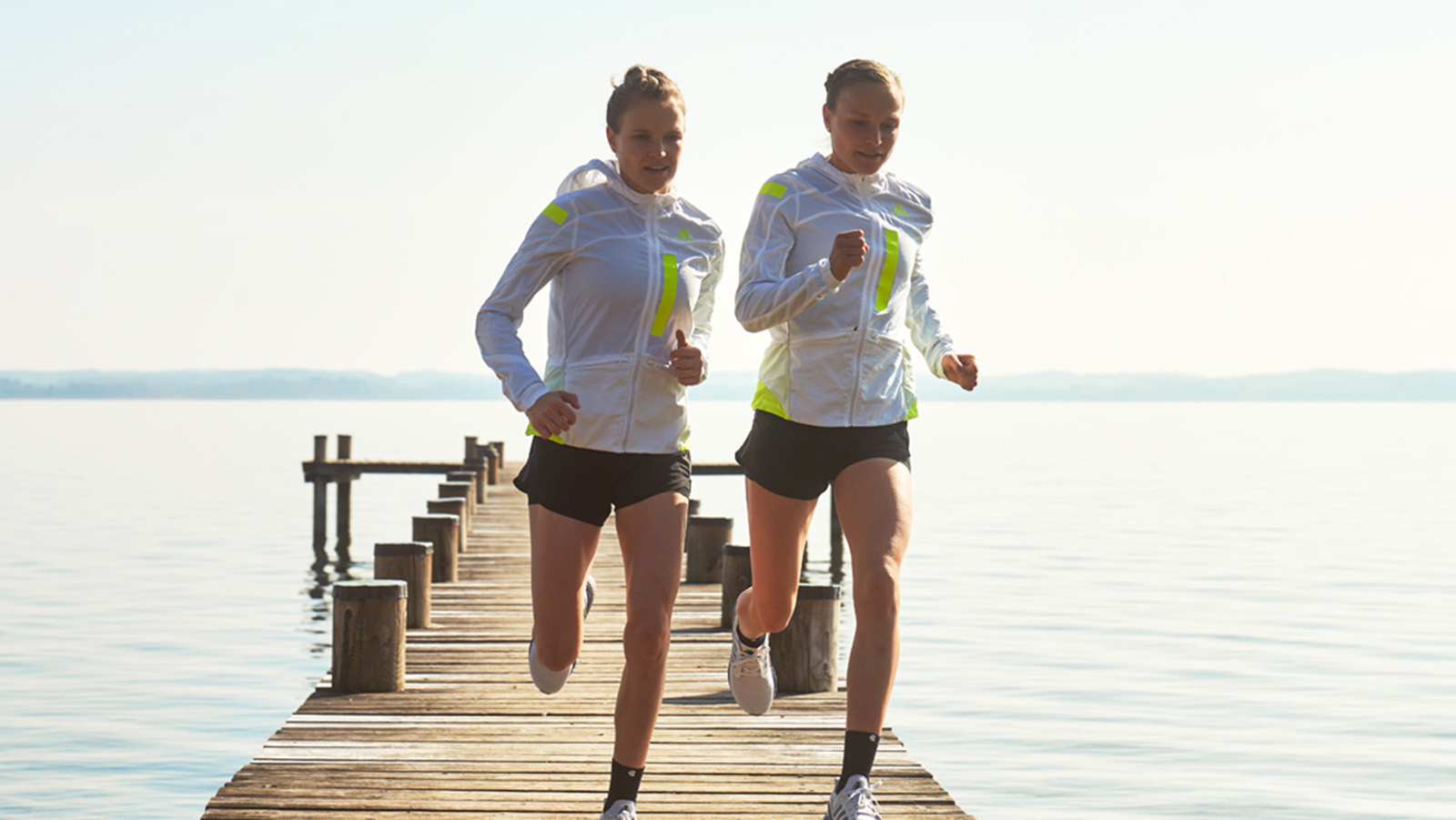 Two women on a morning run together around a lake.