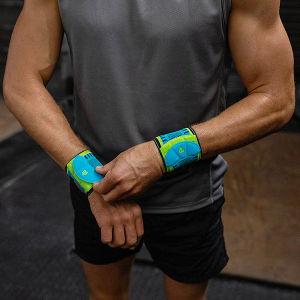 Man adjusting Bauerfeind's Sports Wrist Strap before beginning to exercise in a fitness center.