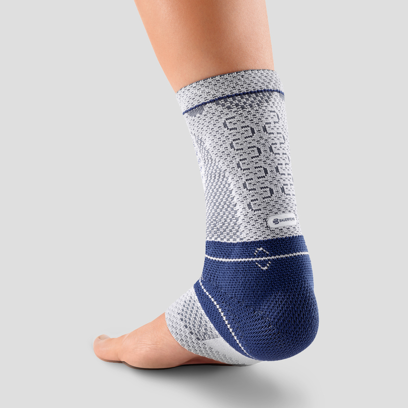 Close-up view of a person wearing a blue and white ankle support brace demonstrating its fit and design on a neutral background