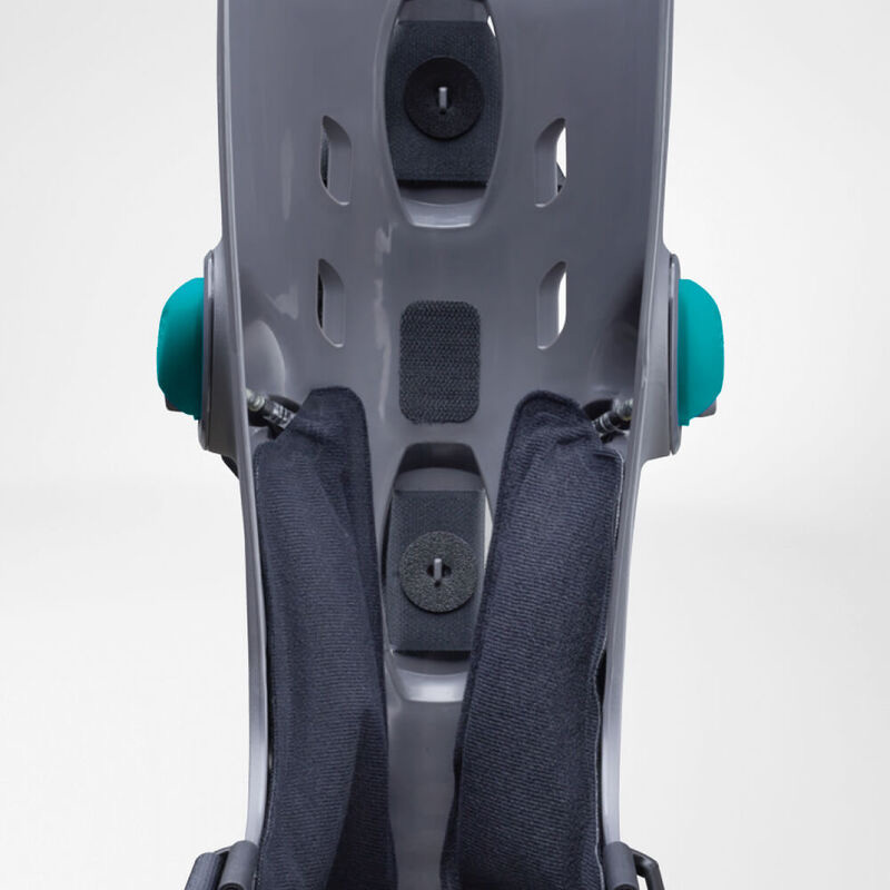 Close-up view of a modern grey baby car seat featuring blue adjustment knobs and textured grey harness straps.