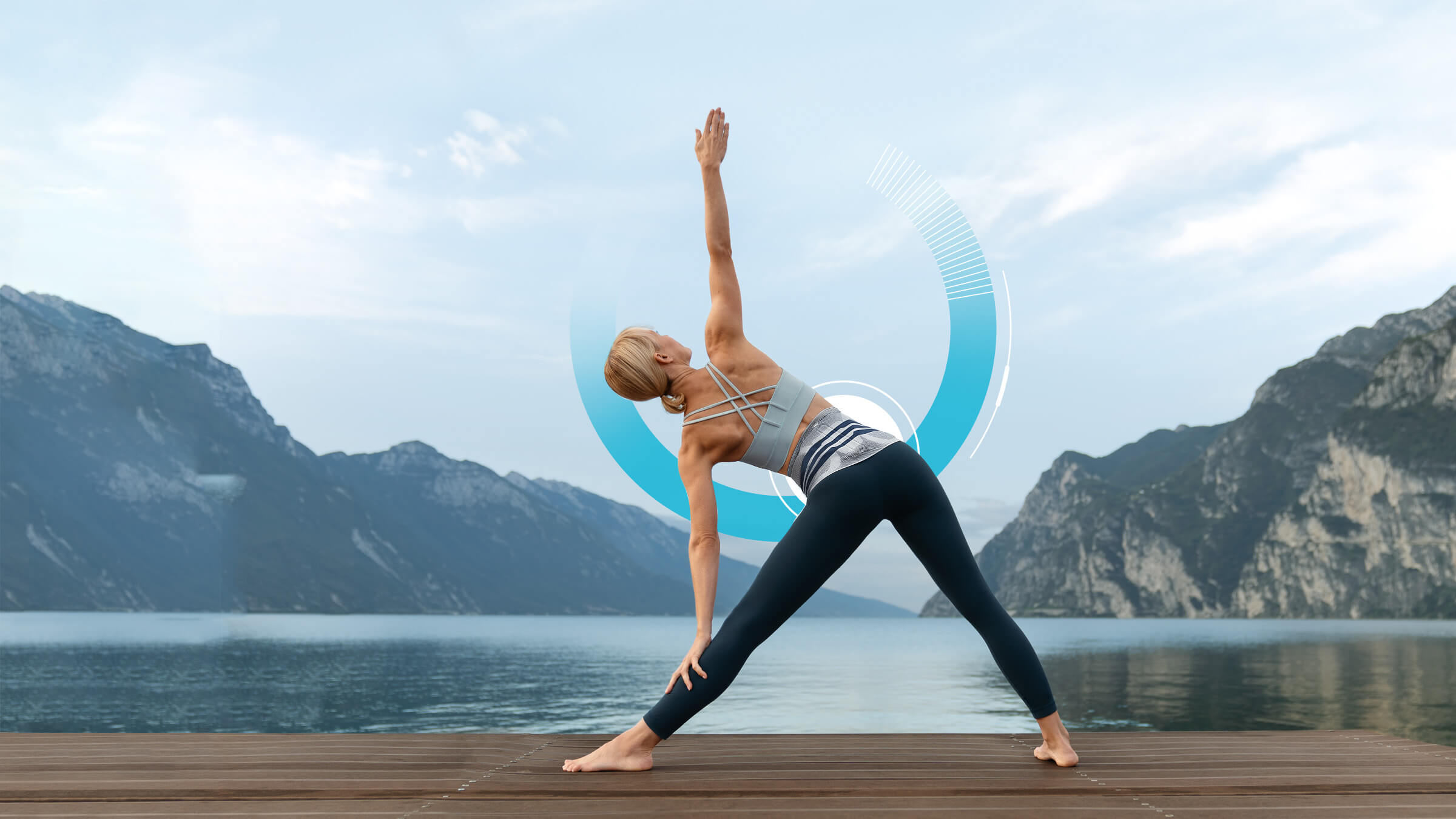 Woman wearing Bauerfeind's LumboTrain waisted back brace while practicing yoga on a dock in front of a lake and mountains.