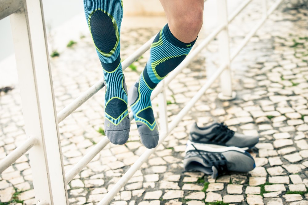 Woman wearing Bauerfeind's Run Performance Compression Socks while running through a city street.