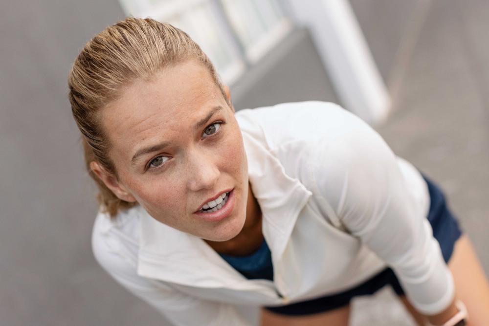 Young woman stretching while wearing Bauerfeind's Run Performance Compression Socks before an inner-city run.