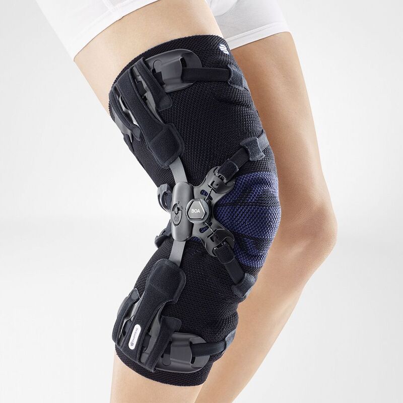 Woman wearing advanced knee brace for joint support and injury recovery, featuring adjustment dials and straps on a white background