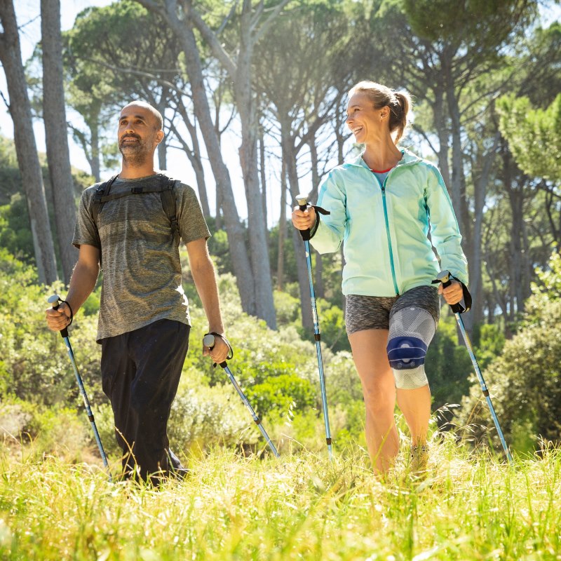 Image of a woman wearing Bauerfeind's GenuTrain A3 arthritis knee brace while hiking with a man.