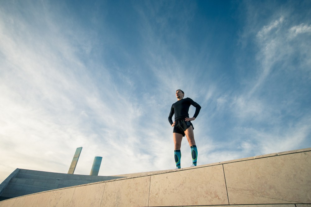 Young woman stretching while wearing Bauerfeind's Run Performance Compression Socks before an inner-city run.