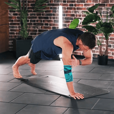 Olympic Gold Medalist Thomas Röhler performing plank taps in a fitness studio while wearing Bauerfeind's Sports Elbow Support.