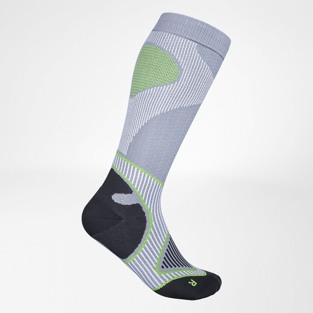 Close-up of a sporty green and yellow striped running sock on a foot, highlighting its breathable fabric and ergonomic design