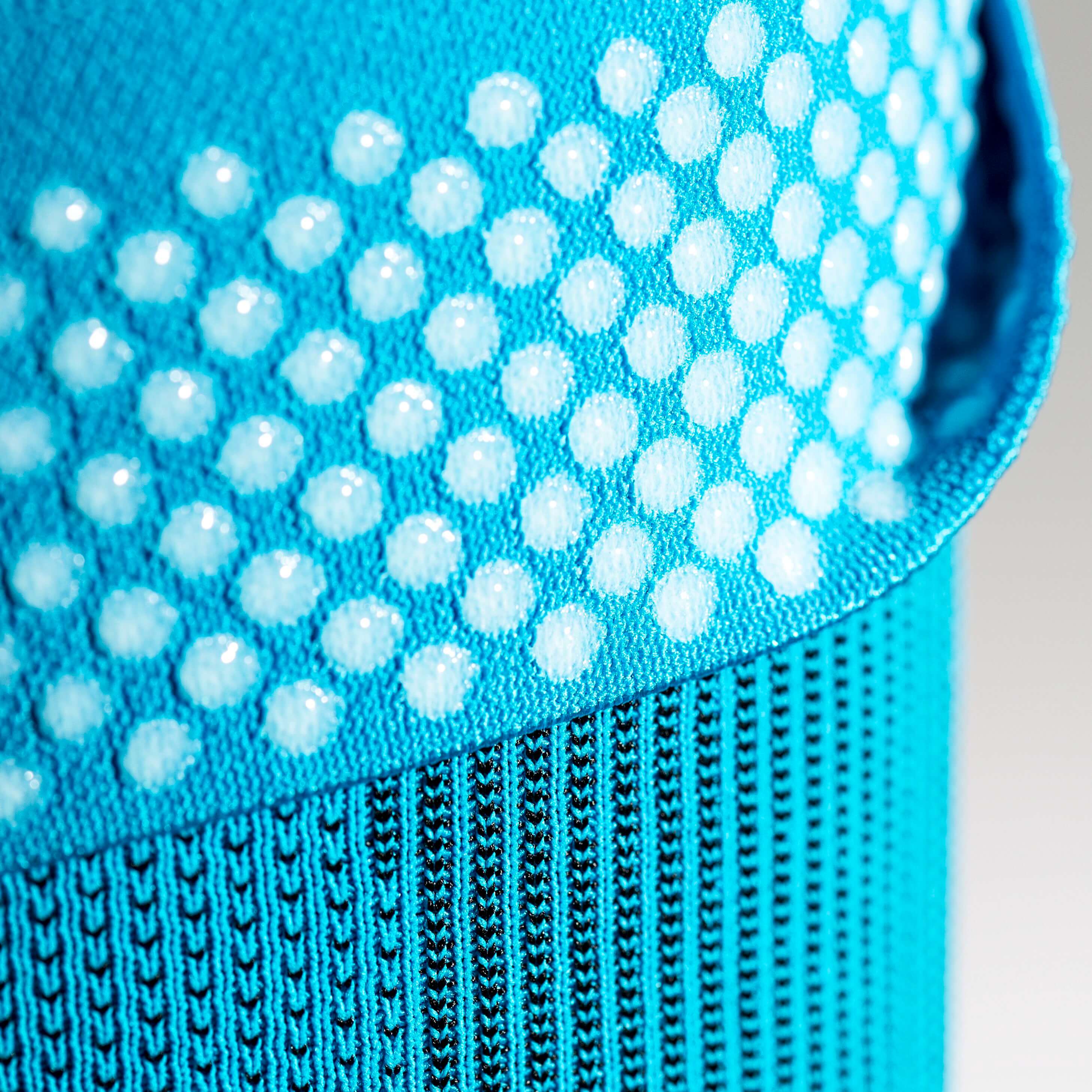 Close-up view of blue fabric with white silicone dots on top of the brace counteracts migration