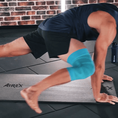 Olympic Gold Medalist Thomas Röhler performing the spider mountain climber exercise in a fitness studio while wearing Bauerfeind's Sports Compression Knee Support.