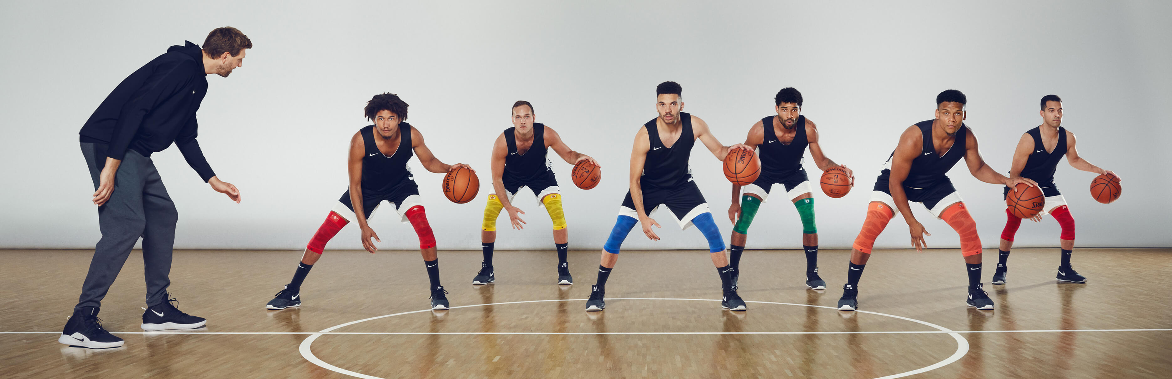 Dirk Nowitzki coaching six basketball players through a drill while they wear Bauerfeind's Sports Compression Knee Support NBA Team Editions.