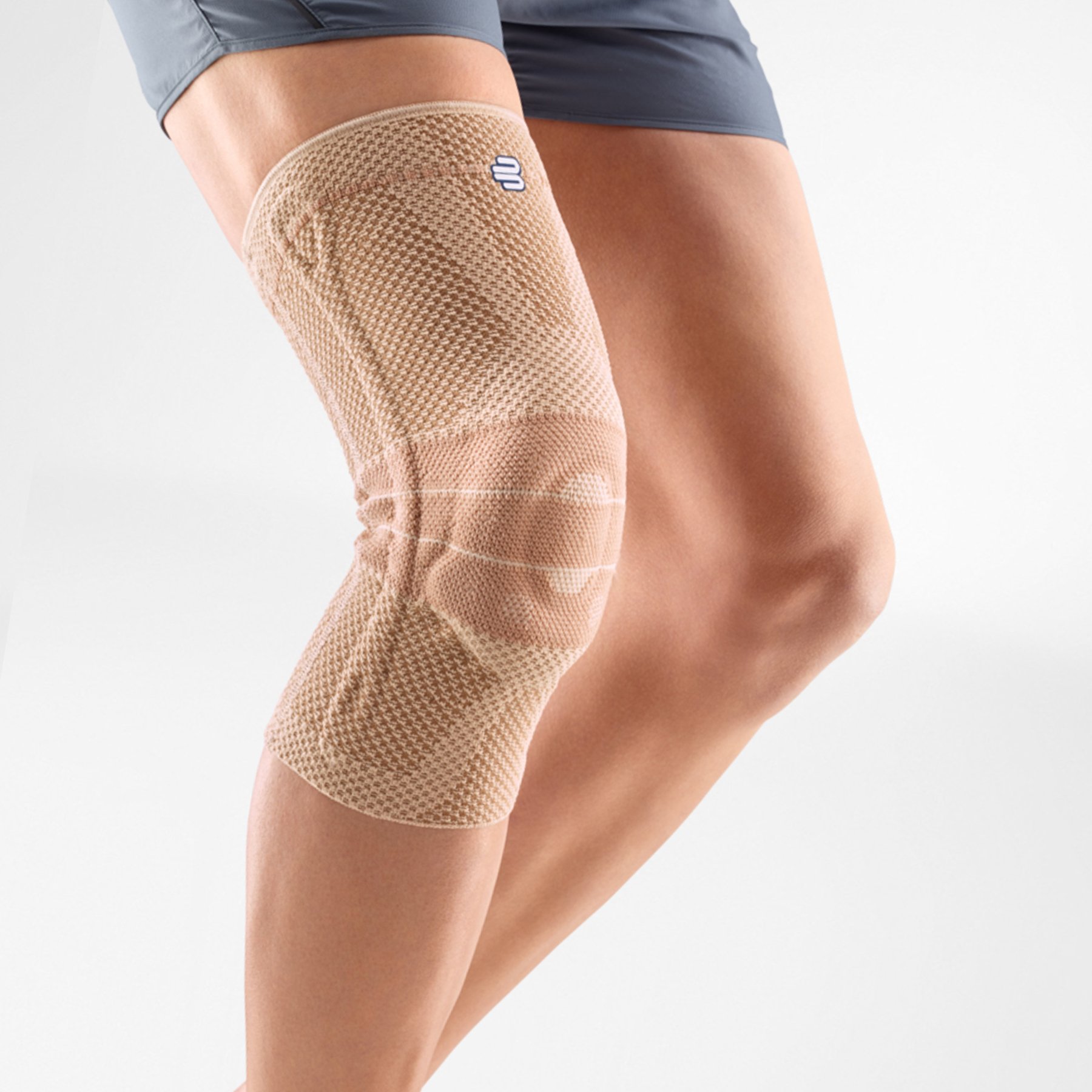 Close-up image of a person wearing Bauerfeind's beige GenuTrain knee brace.