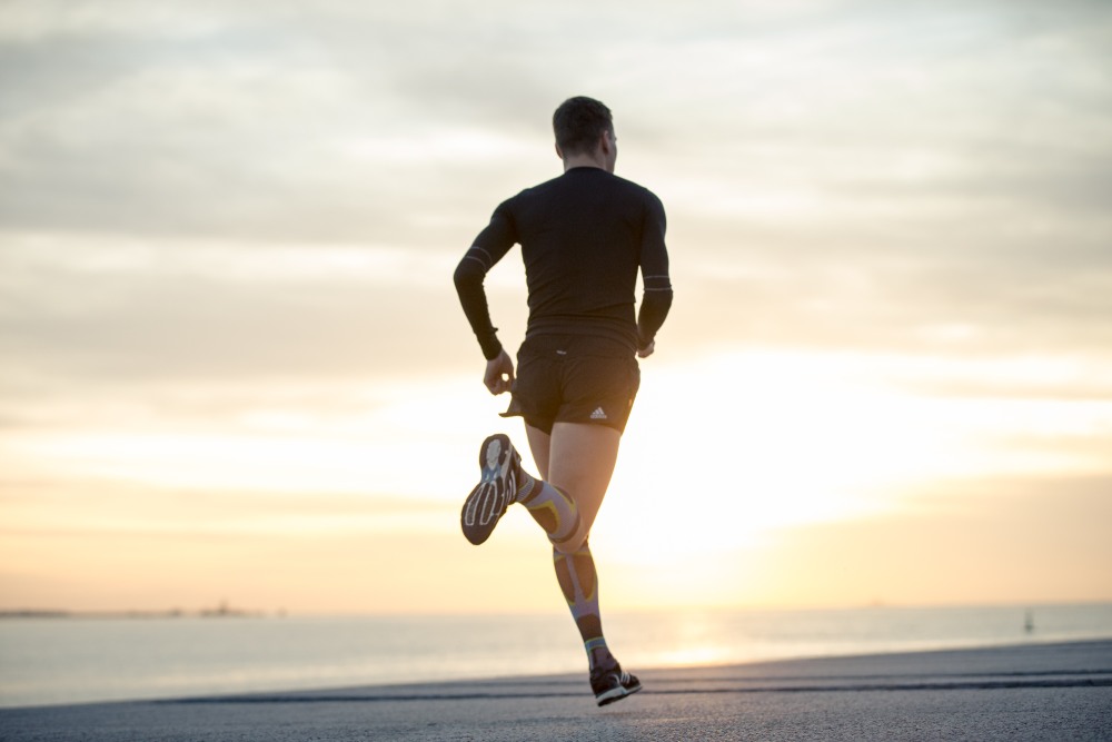 Young woman stretching while wearing Bauerfeind's Run Performance Compression Socks before an inner-city run.