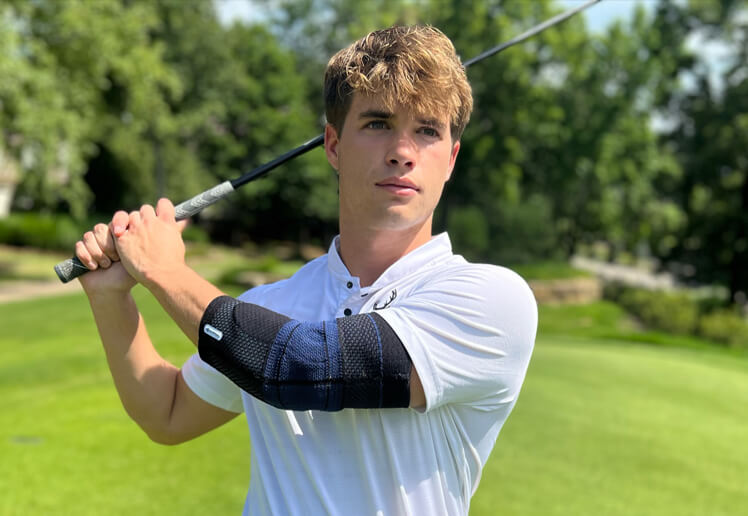 Golfer wearing Bauerfeind's EpiTrain elbow brace while taking a practice swing before teeing off.