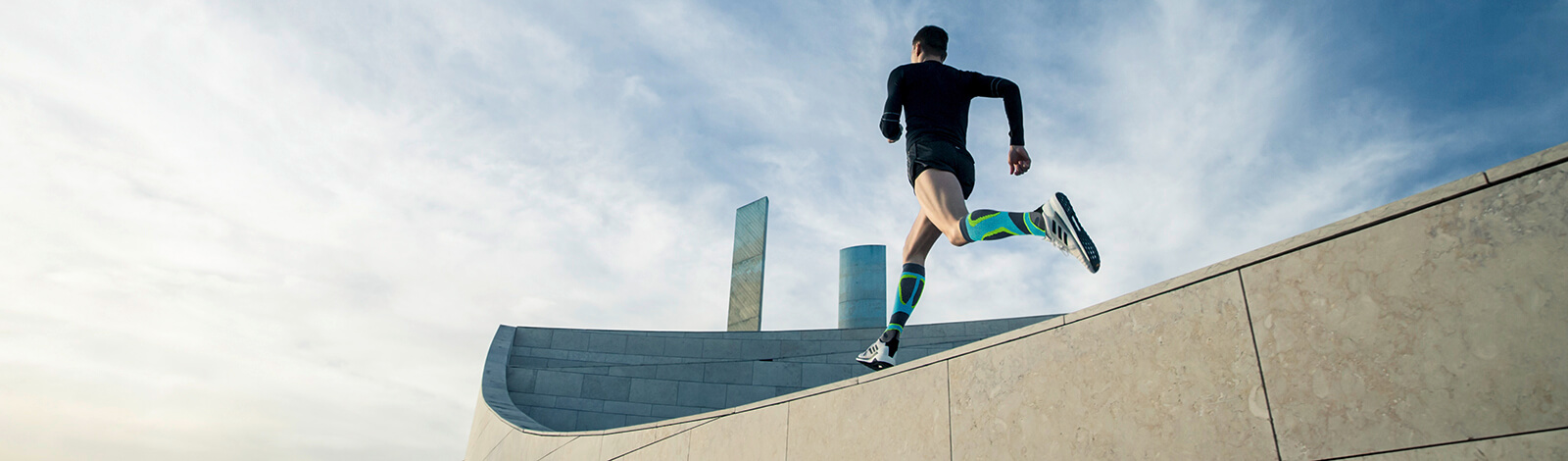 Young woman stretching while wearing Bauerfeind's Run Performance Compression Socks before an inner-city run.